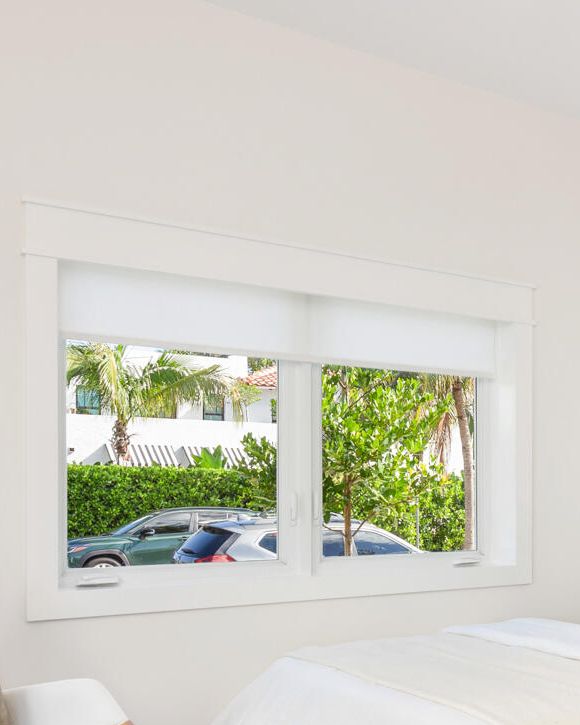 Custom white window casing around a two-lite bedroom window, West Palm Beach