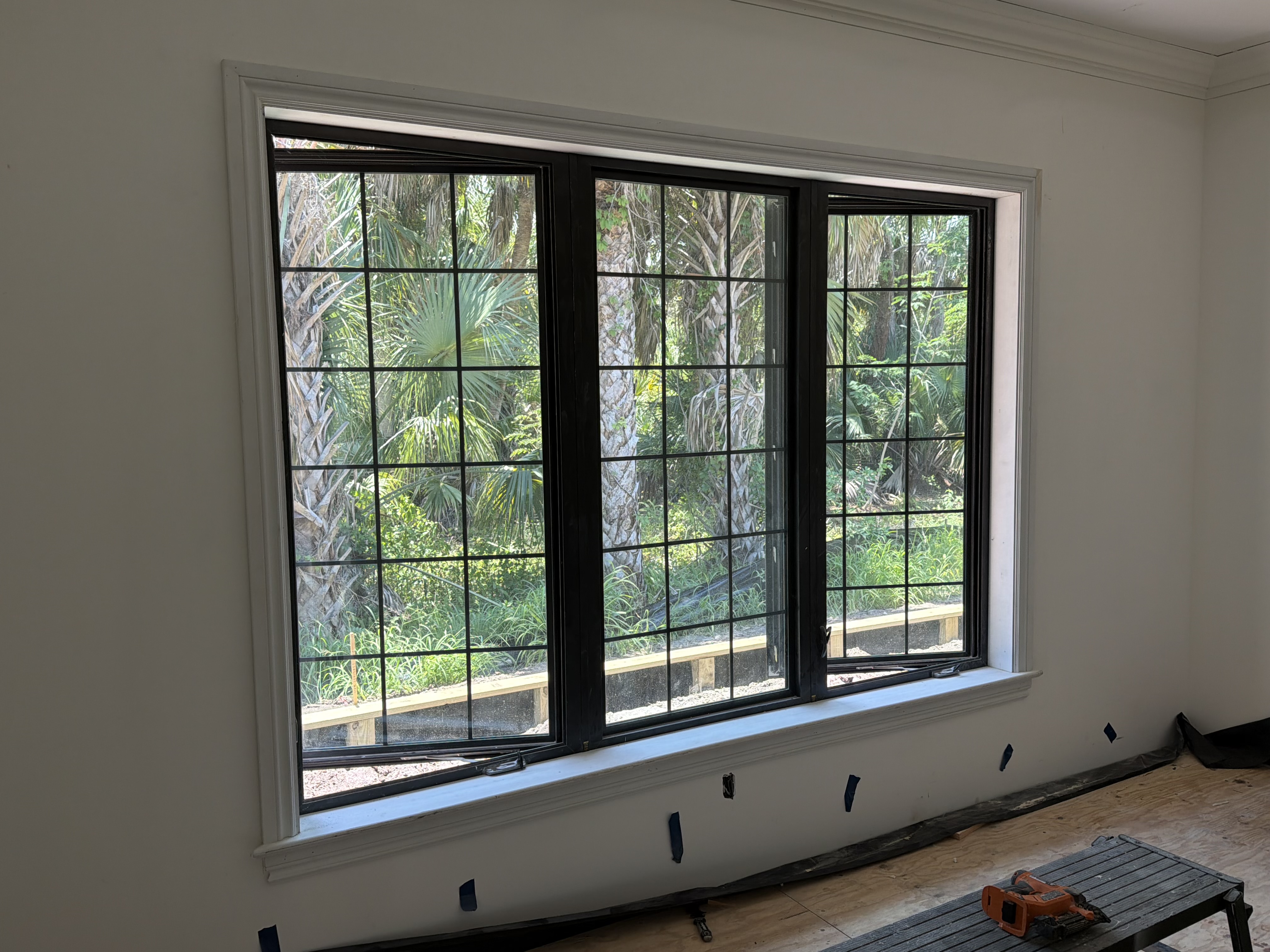 Custom window casing, sill, and apron on a three-lite black grid window